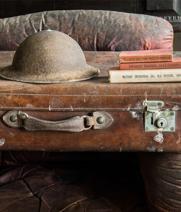 A stack of old books and a helmet on a wooden surface.