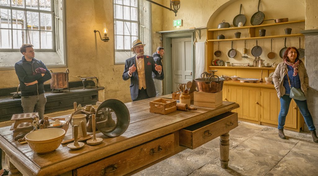 People standing in the company of a tour guide in the kitchen at Fota House.