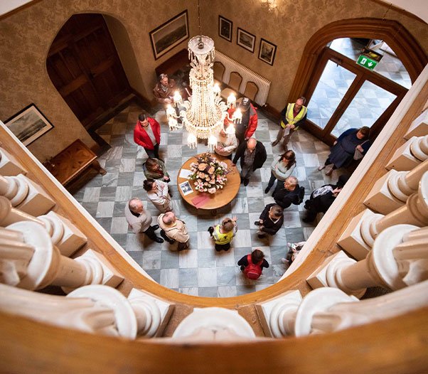 An overhead shot of a tour group underneath an ornate chandelier.