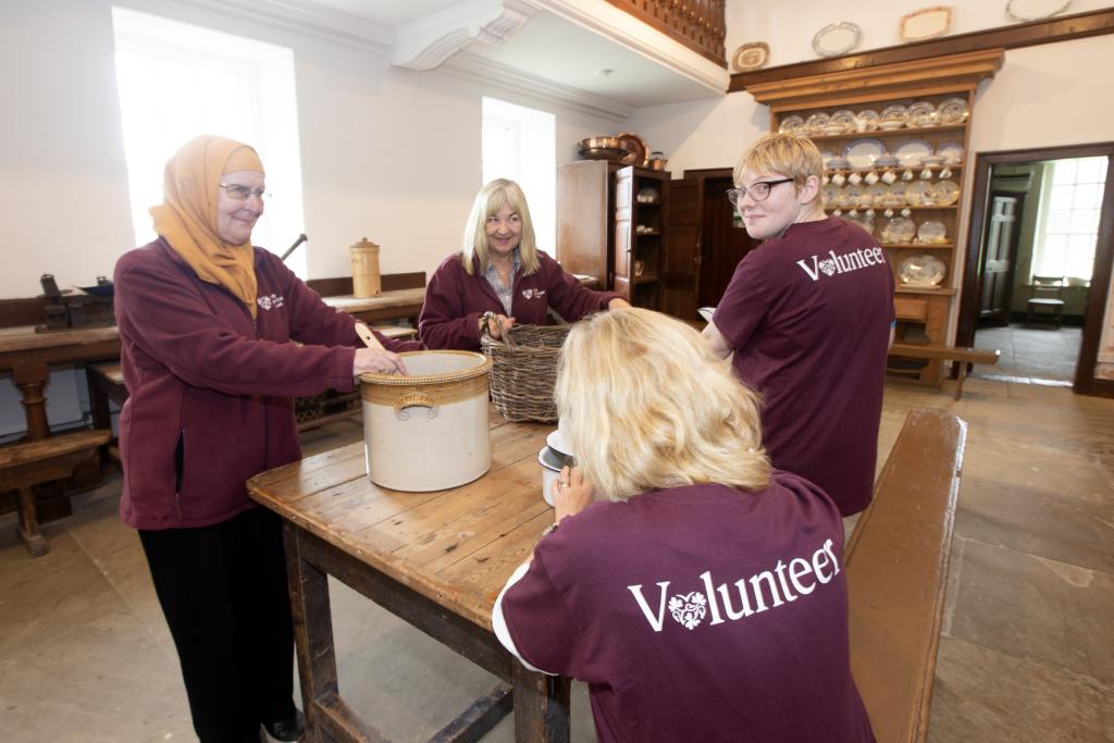 Four female volunteers working in historic kitchen