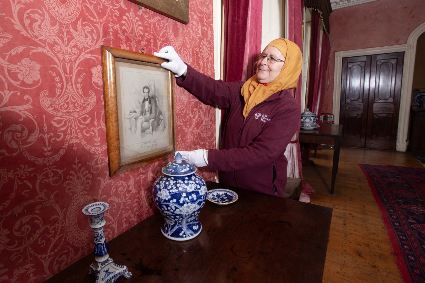 Woman wears white gloves while handling old picture frame