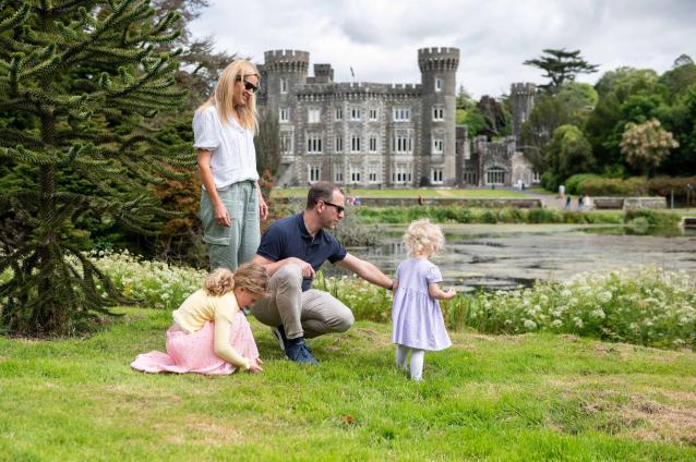 Family of four relaxing in front of lake with gothic revival castle in background