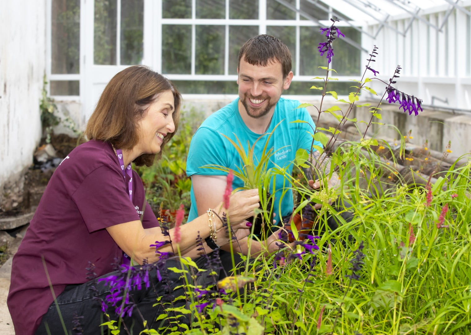 Gardener and volunteer smiling at work in greenhouse