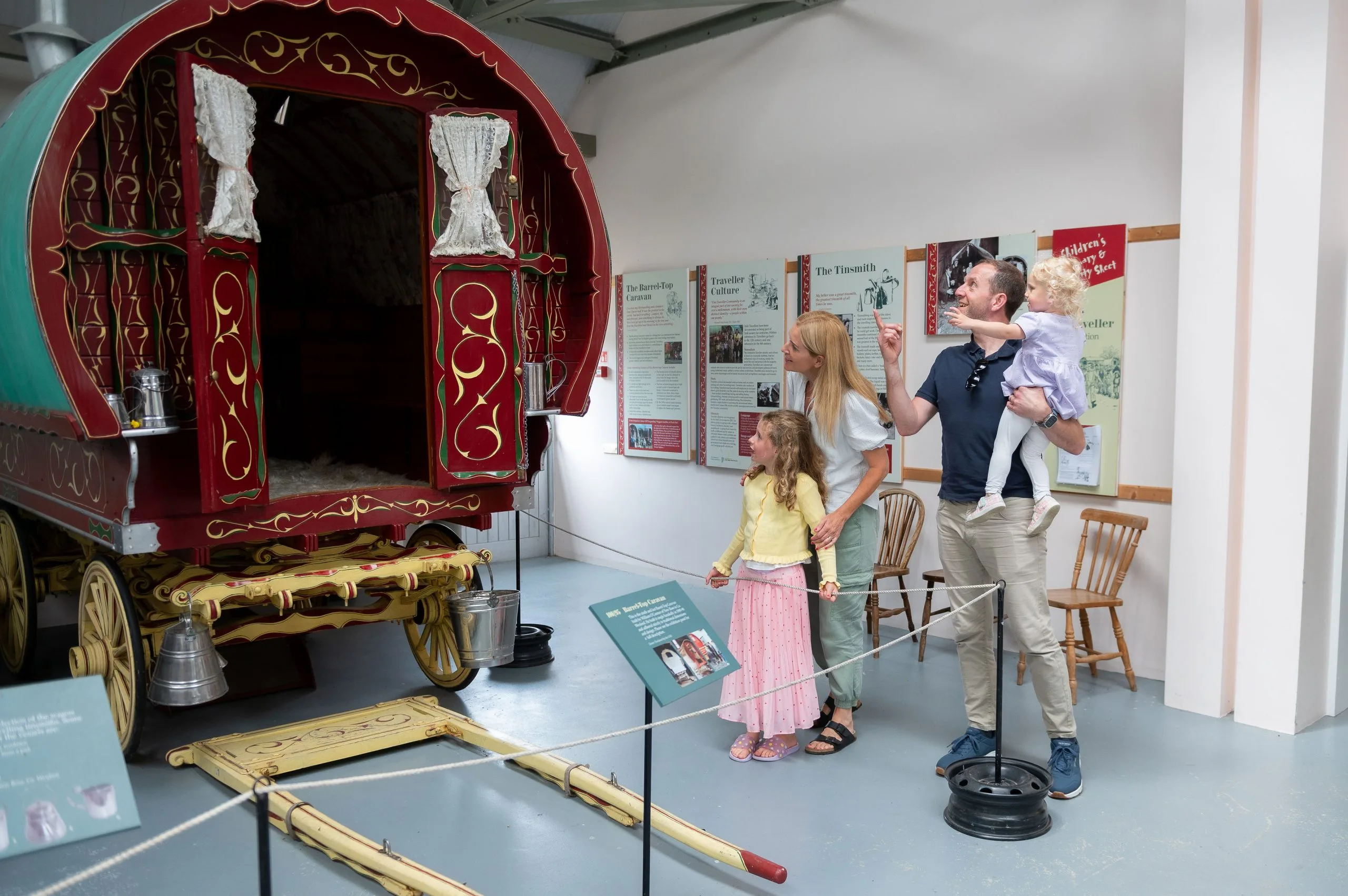 Family of two parents and two young children looking at historic caravan
