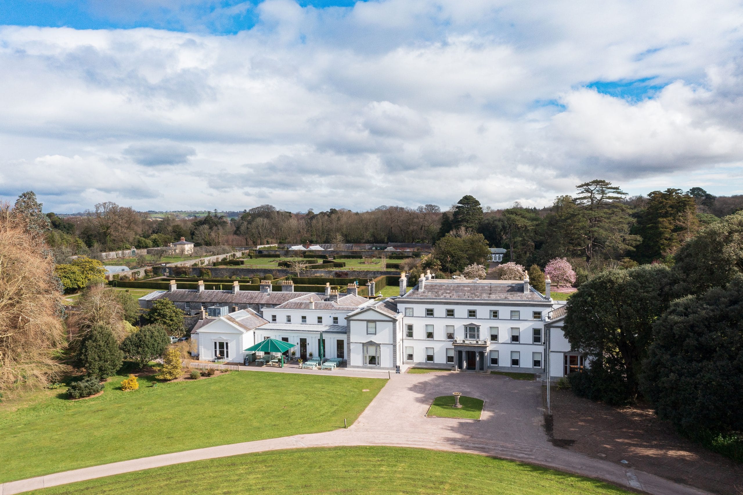 Aerial view of historic mansion with surrounding gardens