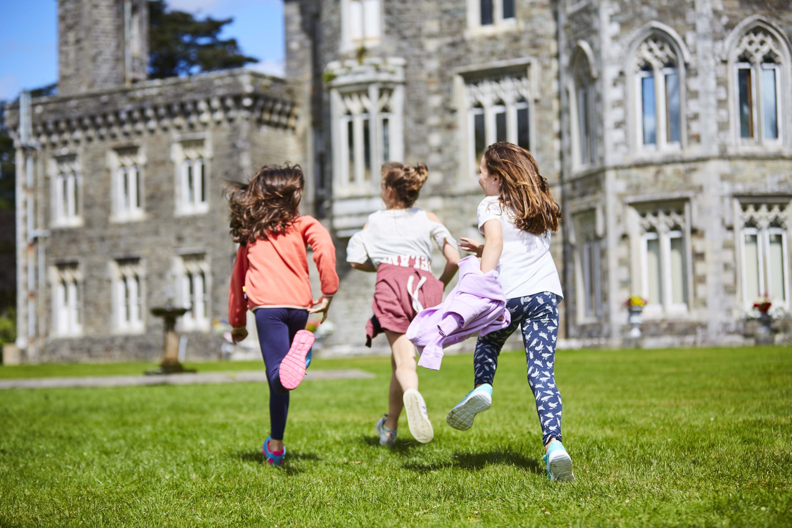 Three girls running towards gothic Johnstown castle 