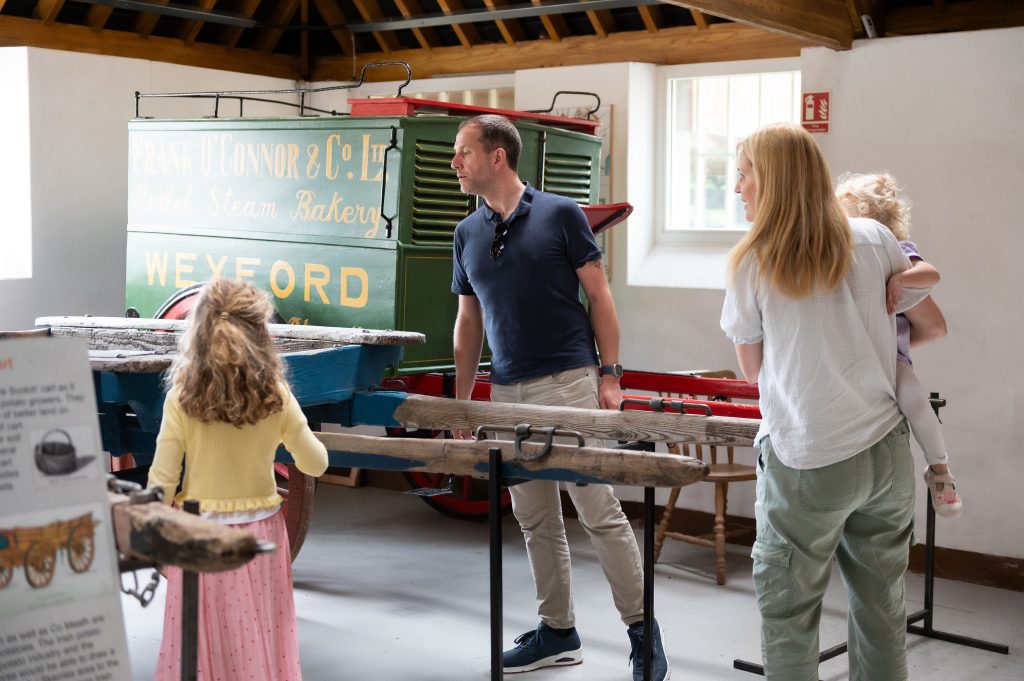 A mother and father with two young children looking at a historic trailer at the Irish Agricultural Museum at Johnstown Castle