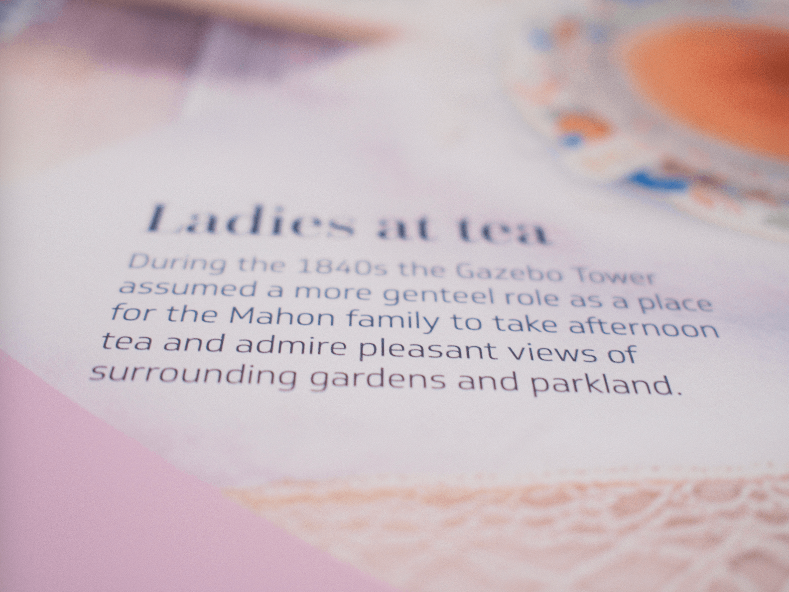 Zoom in of text on a pink table with the headline "Ladies at tea" and a paragraph below that reads "During the 1840s the Gazebo Tower assumed a more genteel role as a place for the Mahon family to take afternoon tea and admire pleasant views of surrounding gardens and parkland."