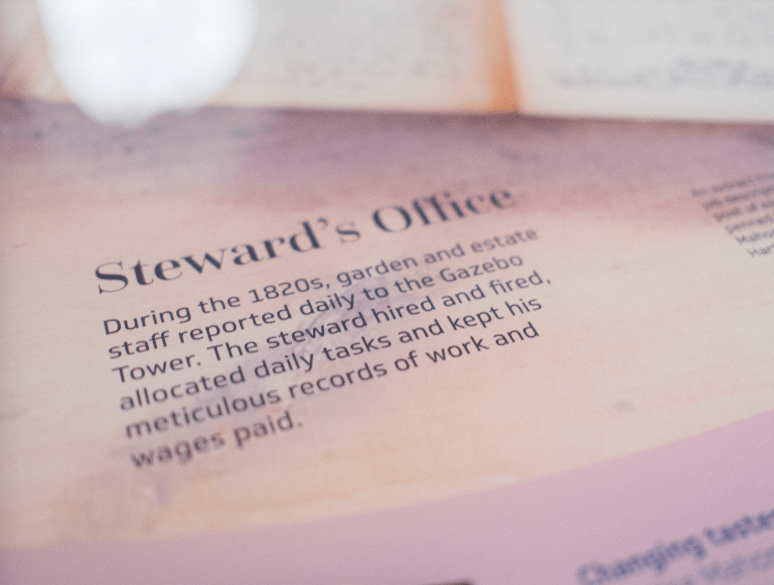 Zoom in on a section of a pink table with the headline "Steward's Office" and a paragraph below reads "During the 1820s, garden and estate staff reported daily to the Gazebo Tower. The steward hired and fired, allocated daily tasks and kept his meticulous records of work and wages paid"