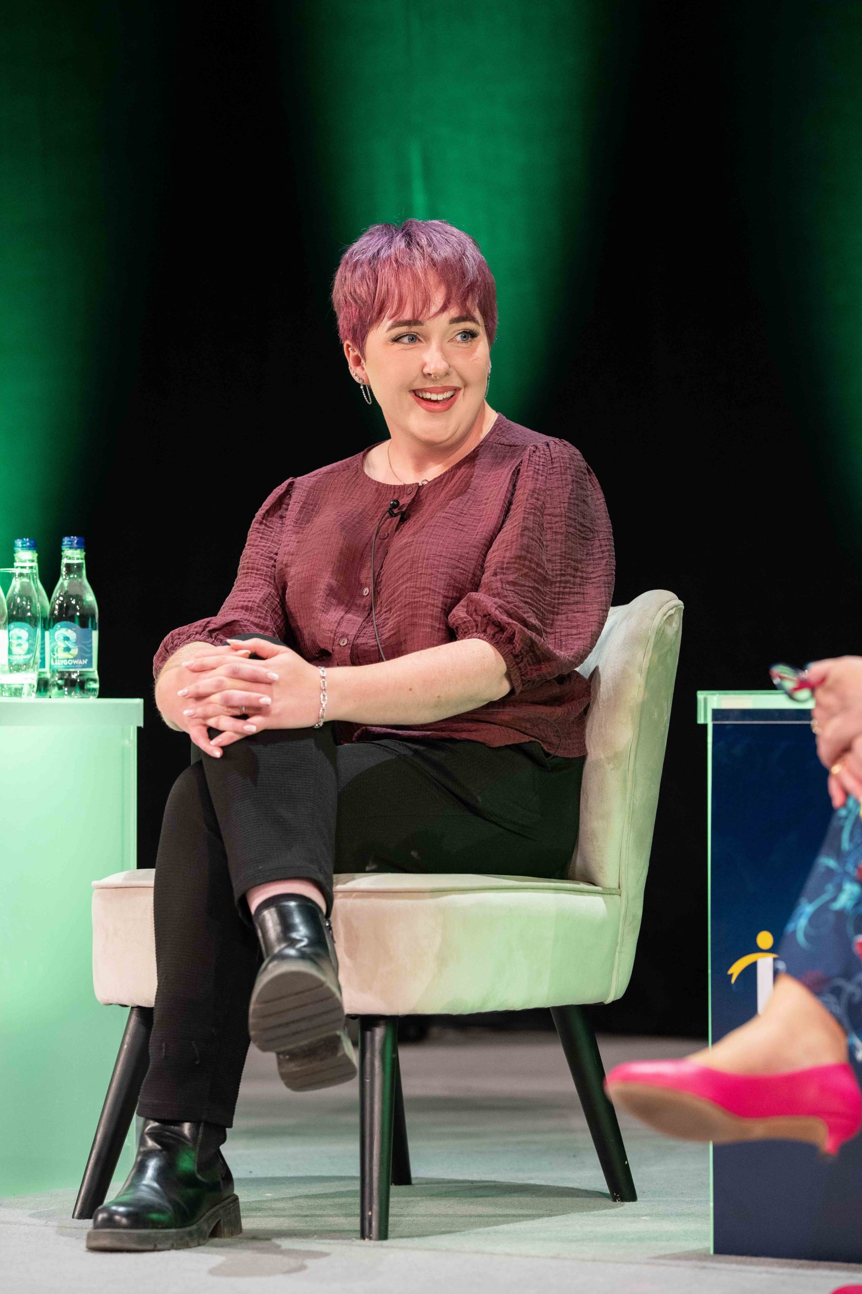 A woman named Jess Sinnott sitting on a chair on stage at ceremony